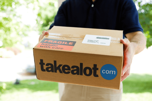 Courier holding out a Takealot.com delivery box outdoors
