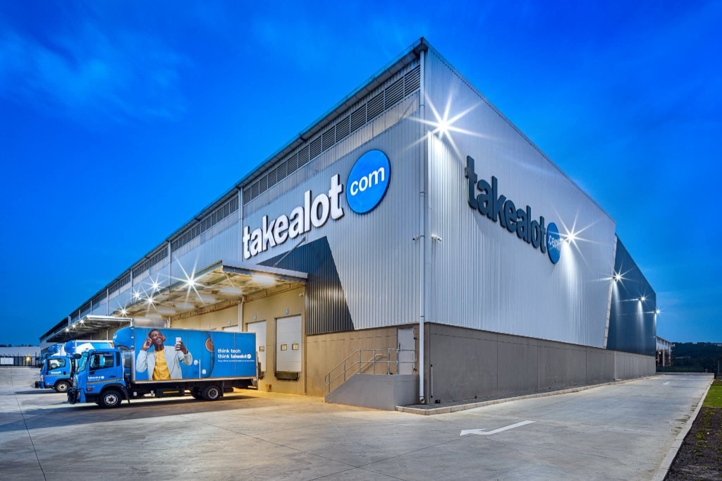 Takealot distribution centre illuminated at dusk with branded trucks