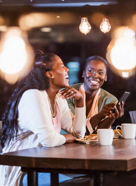 Friends sharing a moment over coffee while looking at a phone