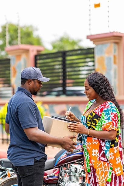 Courier handing a parcel to a smiling customer signing on a tablet